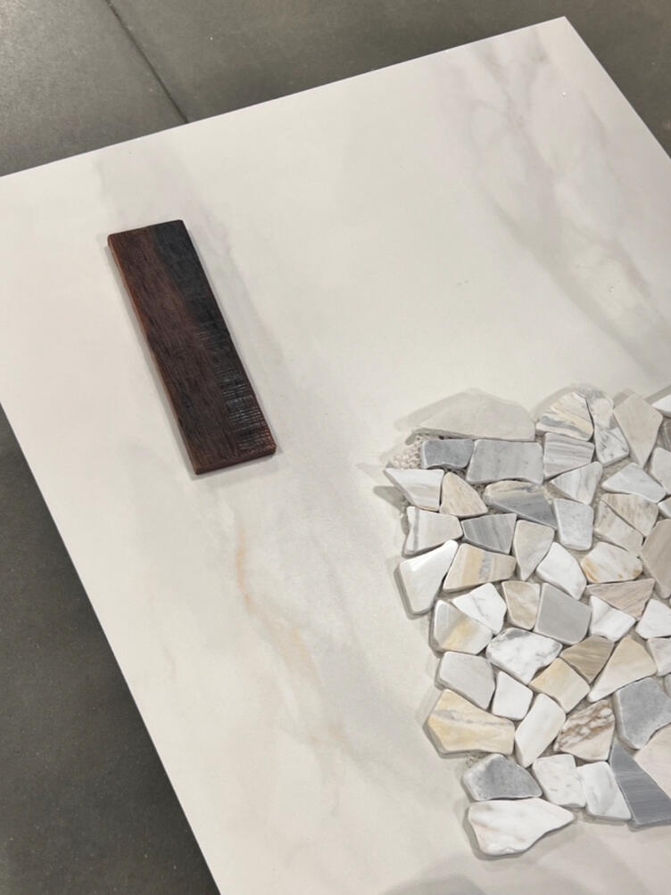 Every finish was intentionally selected to create balance: warm wood tones, soft marble-inspired porcelain, textured stone accents, and contemporary black fixtures.